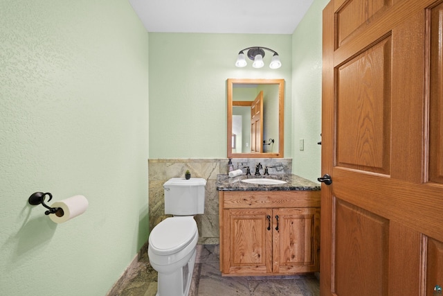 half bathroom with vanity, toilet, and tile walls