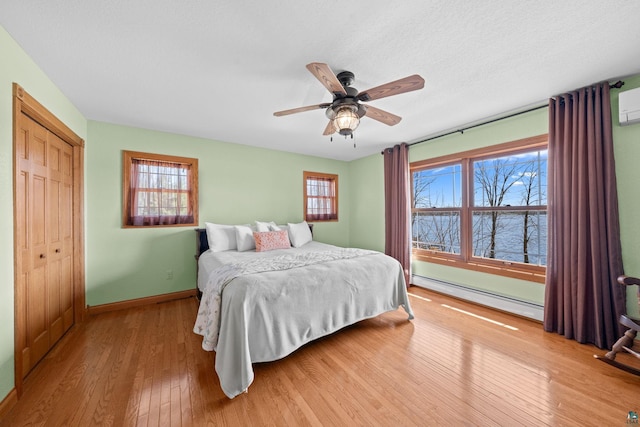 bedroom with a water view, a closet, baseboards, a baseboard heating unit, and wood-type flooring