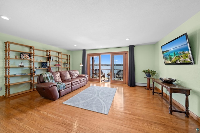 living area featuring recessed lighting, light wood-style flooring, a baseboard heating unit, and baseboards