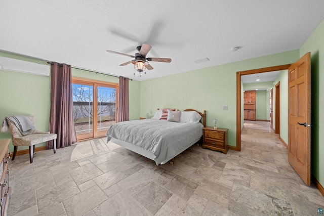 bedroom with visible vents, stone tile flooring, baseboards, a wall mounted AC, and access to outside