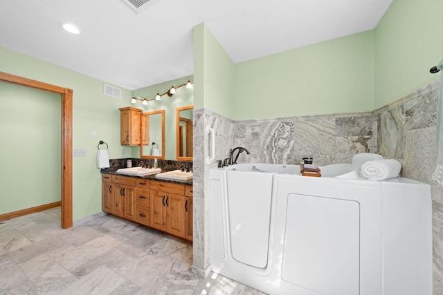 bathroom featuring tile walls, a sink, double vanity, visible vents, and a garden tub