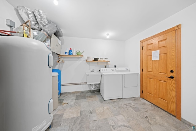 washroom featuring a sink, laundry area, stone finish flooring, water heater, and washer and dryer