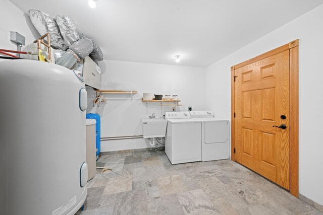 washroom featuring a sink, water heater, laundry area, and washer and clothes dryer