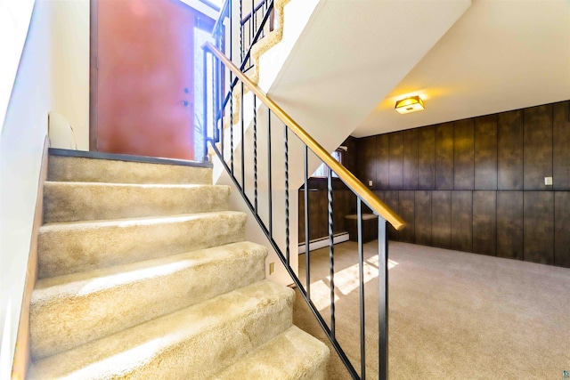 stairs with wooden walls, carpet, and a baseboard radiator