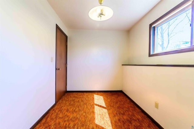 carpeted empty room featuring baseboards