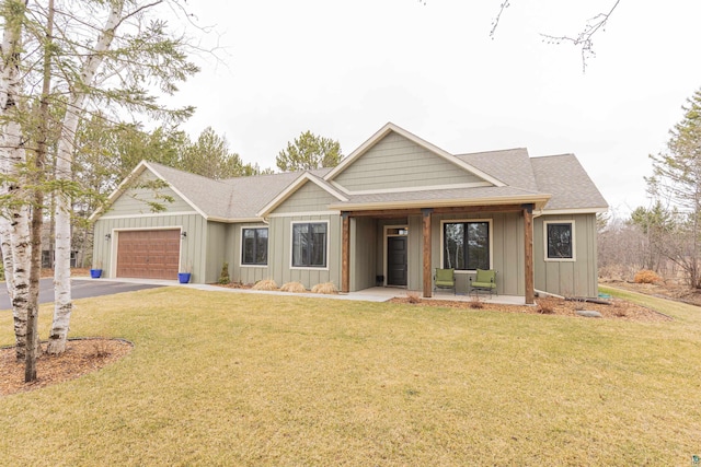 view of front facade featuring board and batten siding, an attached garage, driveway, and a front yard