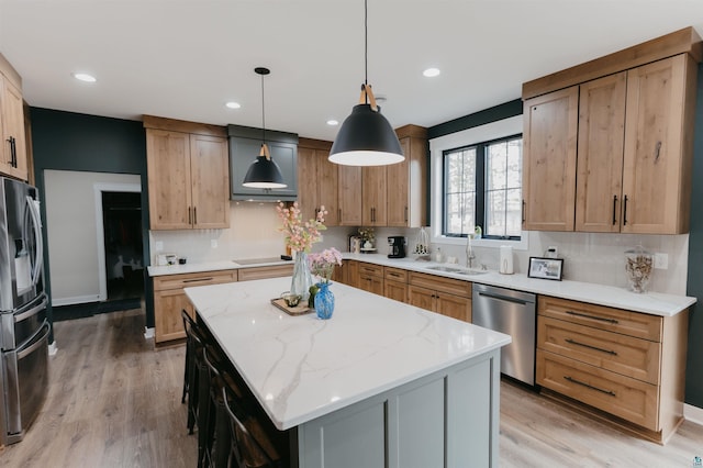 kitchen featuring a sink, a kitchen island, stainless steel appliances, and light wood-type flooring