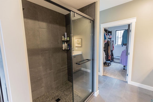 full bath featuring vanity, baseboards, a shower stall, and a walk in closet