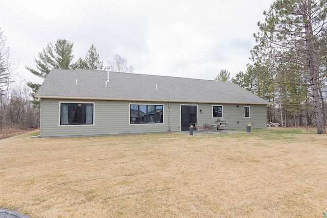 rear view of property with a shingled roof, a patio area, and a yard