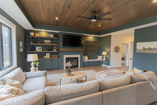 living area featuring a fireplace, a ceiling fan, baseboards, wooden ceiling, and light wood-type flooring