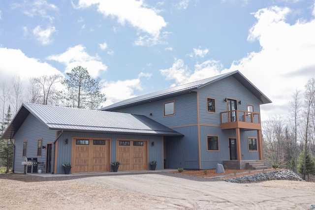 view of front of property with a standing seam roof, driveway, metal roof, a balcony, and an attached garage