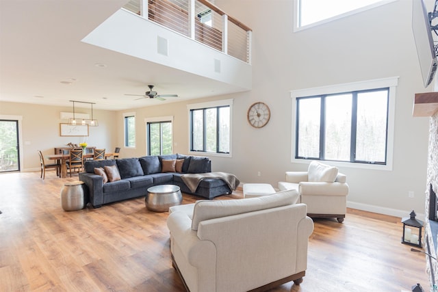 living area featuring a ceiling fan, baseboards, and wood finished floors