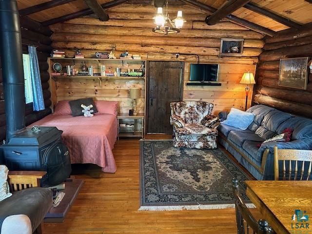 bedroom featuring wooden ceiling, lofted ceiling with beams, a wood stove, and log walls