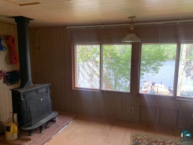unfurnished dining area with a wood stove and wood walls