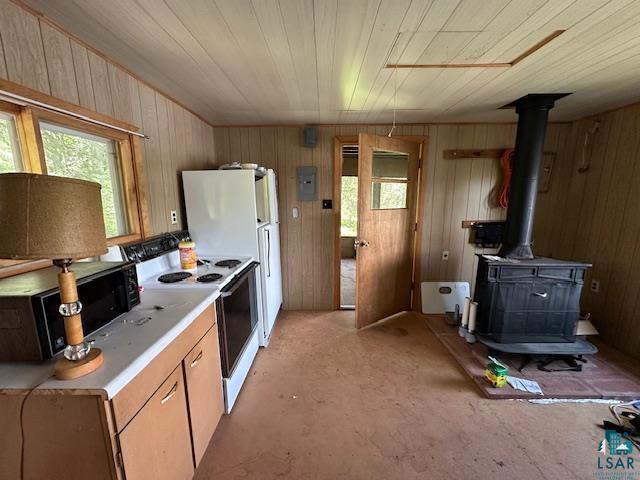 kitchen featuring light countertops, a healthy amount of sunlight, a wood stove, and electric range oven
