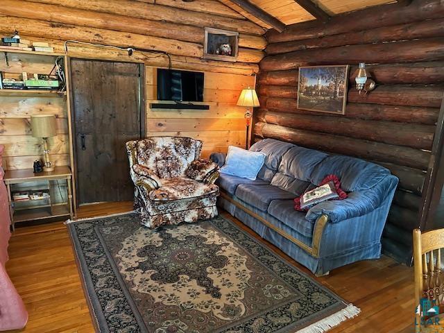 living area with wooden ceiling, log walls, vaulted ceiling with beams, and wood-type flooring