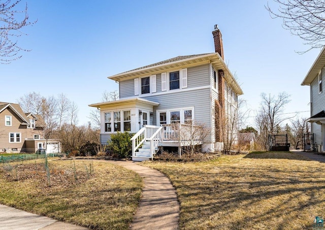 traditional style home featuring a deck, a chimney, and a front lawn