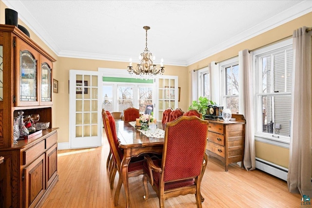 dining space with an inviting chandelier, crown molding, a baseboard heating unit, and light wood-type flooring