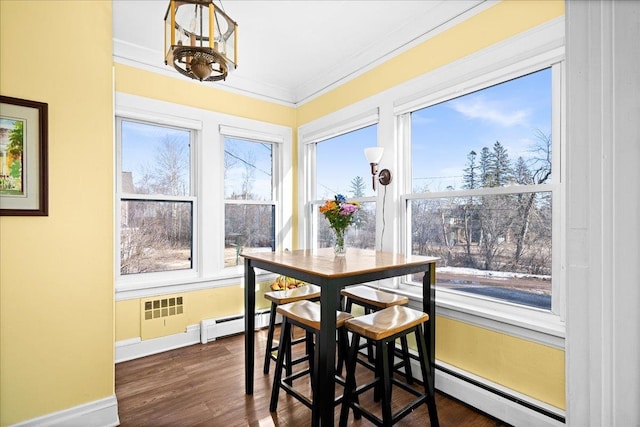 dining area featuring baseboards, ornamental molding, a baseboard heating unit, and dark wood-type flooring