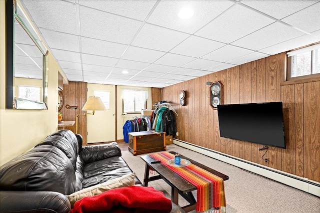carpeted living area featuring wood walls, a paneled ceiling, and a baseboard heating unit