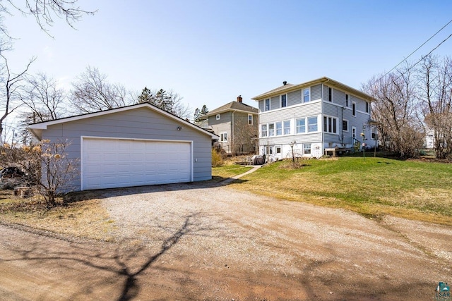 view of front facade with a front lawn, an outbuilding, driveway, and a detached garage