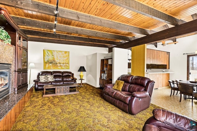 living room featuring wood ceiling, a glass covered fireplace, and beam ceiling
