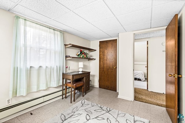 home office with baseboards, baseboard heating, and a drop ceiling