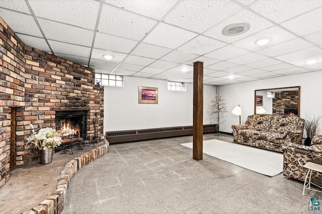 living area with a paneled ceiling, a brick fireplace, and a baseboard heating unit
