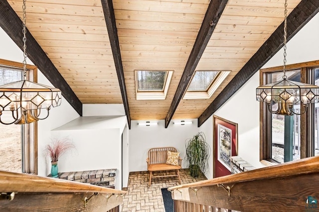 interior space featuring an inviting chandelier, beamed ceiling, wood ceiling, brick floor, and a skylight