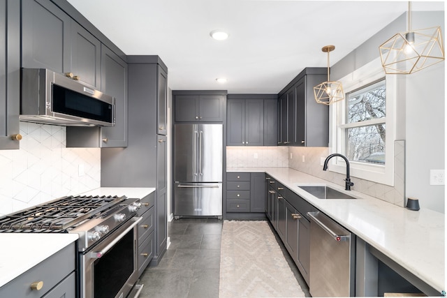 kitchen with hanging light fixtures, tasteful backsplash, a sink, premium appliances, and recessed lighting