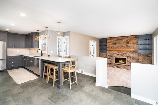 kitchen with plenty of natural light, a peninsula, a sink, and appliances with stainless steel finishes