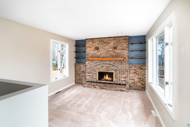 unfurnished living room with baseboards, plenty of natural light, a fireplace, and carpet floors