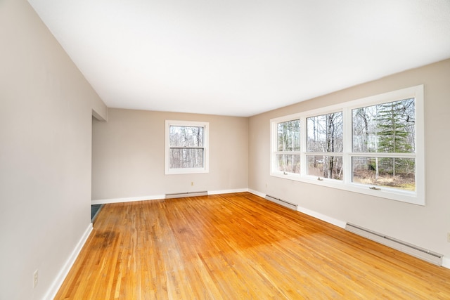 spare room with baseboards, light wood-style flooring, and baseboard heating