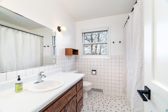 full bathroom with wainscoting, vanity, toilet, tile walls, and visible vents