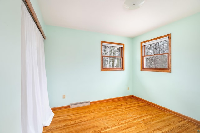 empty room featuring baseboards, light wood-type flooring, and visible vents
