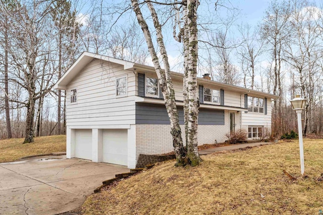 view of property exterior with an attached garage, brick siding, a chimney, a yard, and driveway