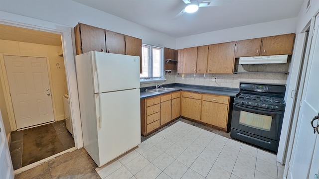 1441 90th Ave W, Duluth, MN 55808 - kitchen with freestanding refrigerator, dark countertops, black gas stove, under cabinet range hood, and a sink