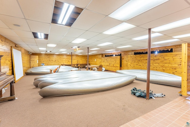 interior space featuring carpet flooring, wood walls, and a paneled ceiling