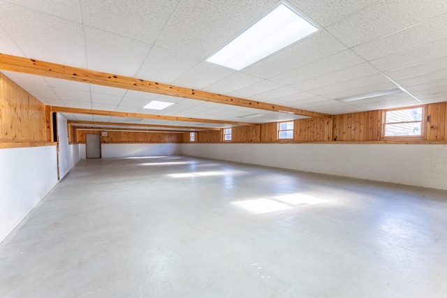basement with wood walls and a paneled ceiling