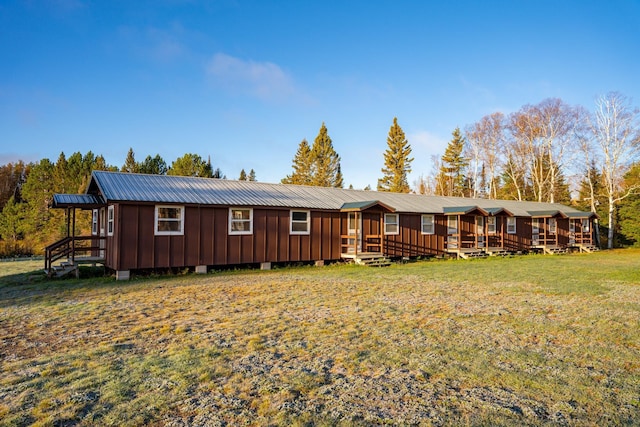 rear view of house with a lawn, board and batten siding, and metal roof