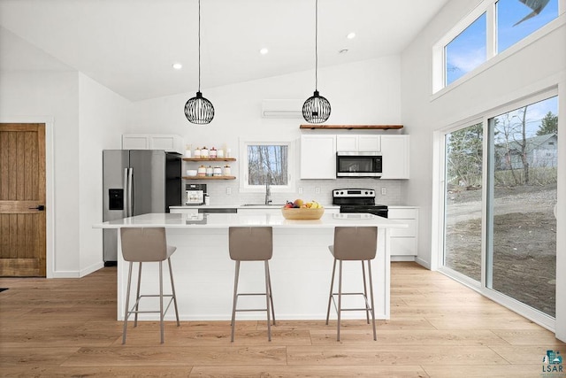 kitchen featuring decorative backsplash, a kitchen island, a kitchen bar, appliances with stainless steel finishes, and white cabinetry