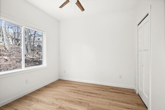 spare room featuring baseboards, ceiling fan, and light wood-type flooring