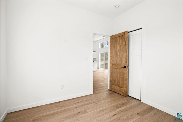 spare room featuring baseboards and light wood finished floors