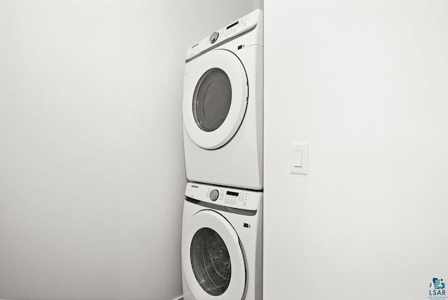 clothes washing area featuring stacked washing maching and dryer and laundry area