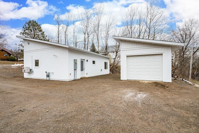rear view of property with a garage, an outdoor structure, and driveway