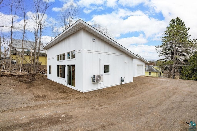 view of side of home with a garage, ac unit, and dirt driveway
