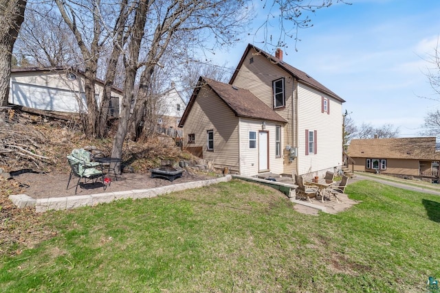 rear view of property with a yard, a patio, and a chimney