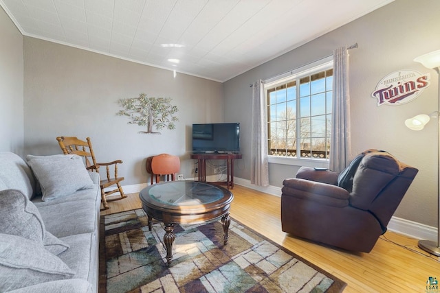 living room featuring crown molding, baseboards, and wood finished floors