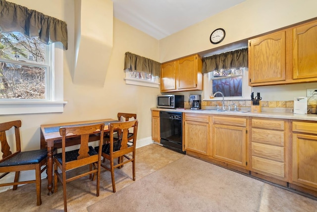 kitchen featuring a sink, light countertops, stainless steel microwave, and black dishwasher