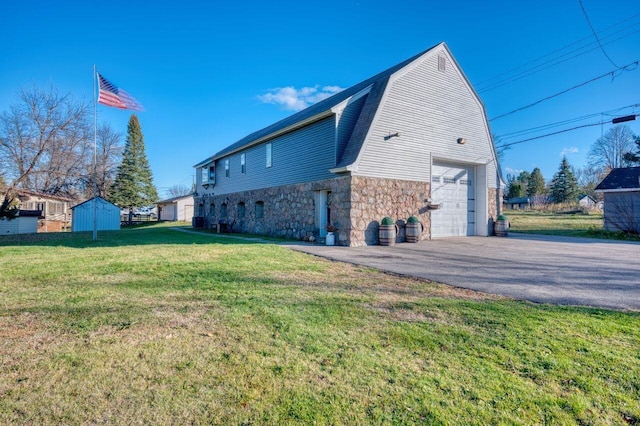view of property exterior featuring a gambrel roof, stone siding, a garage, a lawn, and driveway